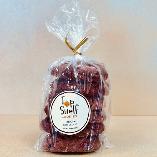 A pack of red velvet cookies with a clear wrapper on top, labeled 'Top Shelf Cookies - Red Line'.