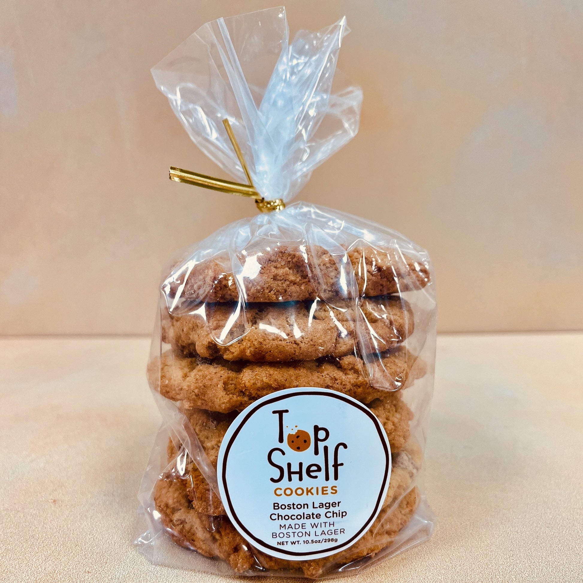 Packaged chocolate chip cookies in a clear plastic bag with a gold tie, labeled 'Top Shelf Cookies - Boston Lager Chocolate Chip'.