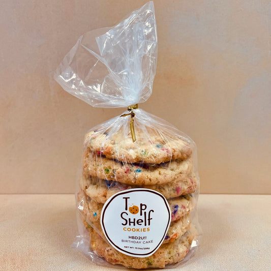 A pack of Top Shelf Cookies HBD2U!! birthday cookies stacked and wrapped in a clear plastic bag, with a gold-colored twist tie on top.