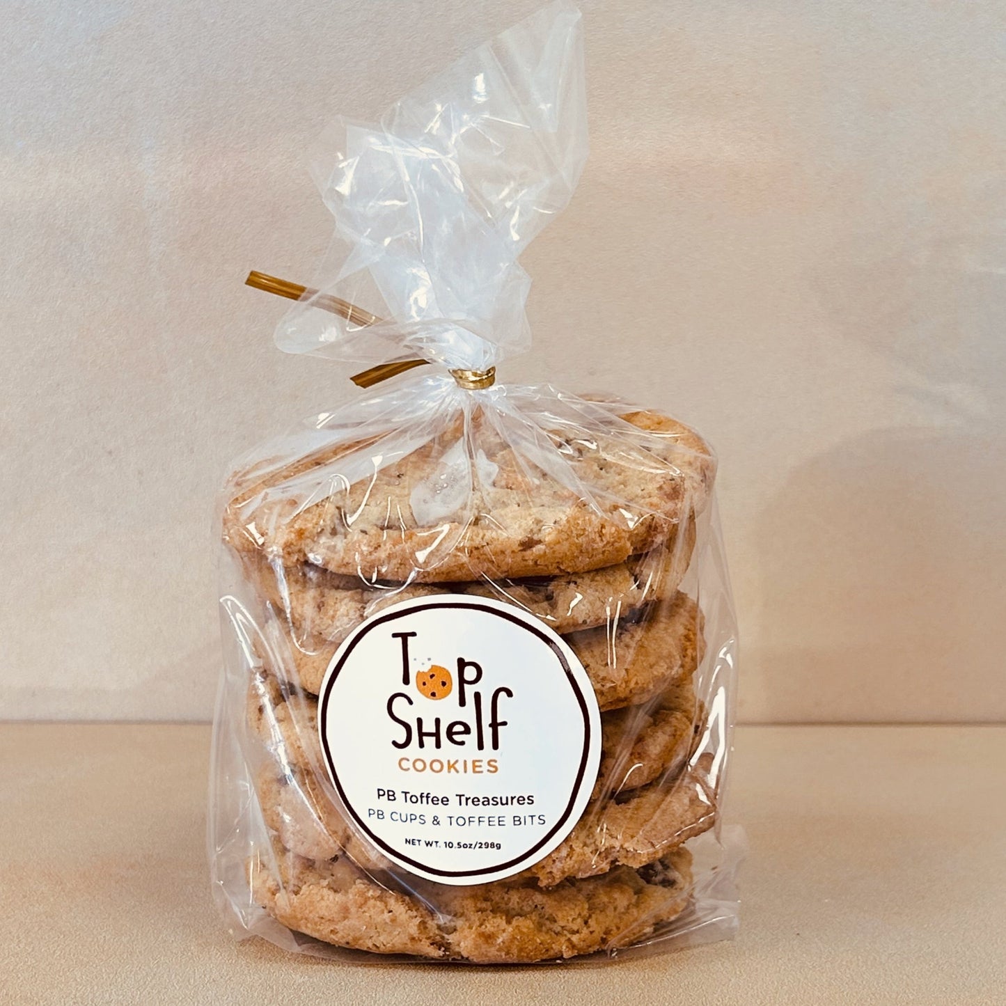 Packaged cookies labeled 'Top Shelf Cookies' in a clear plastic bag labeled PB Toffee Treasures